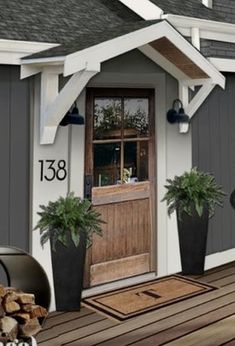 the front porch is painted gray and has potted plants on it, along with an outdoor fireplace