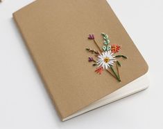 a book with flowers on it sitting on top of a white table next to scissors