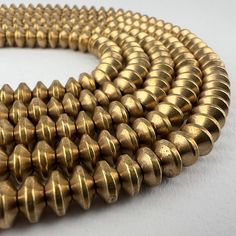 A strand of brass bicone spacer beads. 145 beads 24" of beads 60cm 7mm diameter 4mm tall 2mm hole Focal Beads, Oct 11, Focal Bead, Spacer Beads, Halloween Shopping, Seattle, Accessory Gift, Electronic Accessories, Brass