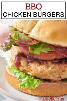 a chicken burger with lettuce, tomato and bacon on a bun that is sitting on a plate