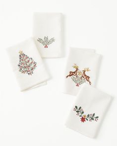 four white christmas napkins with embroidered designs