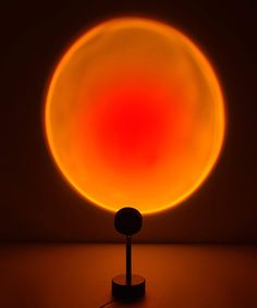 an orange and red ball sitting on top of a black stand in front of a dark background