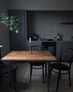 a wooden table with two chairs and a candle on it in front of a potted plant