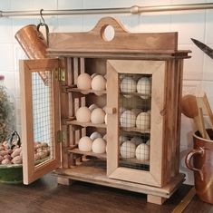 a wooden cabinet with eggs in it on a table next to a potted plant