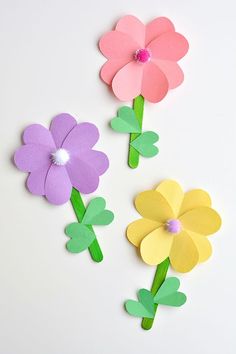 three paper flowers are shown on a white surface, one is pink and the other is yellow