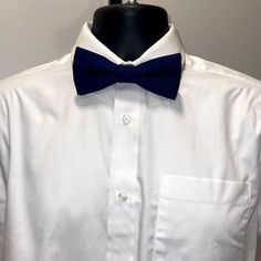 The item is a pretied adjustable navy blue cotton bow tie.  The item would be a great accessory to wear with a blazer or simply with just a shirt and slacks. Dapper Blue Bow For Black Tie Events, Blue Adjustable Bow Tie And Suit Accessories, Classic Blue Bow Tie, Blue Standard Bow Tie For Black Tie Events, Blue Bow Tie For Black Tie Events, Classic Blue Bow Tie And Suit Accessories, Blue Standard Bow Tie For Father's Day, Dapper Blue Bow With Ties, Blue Bow Tie For Father's Day