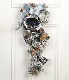 a christmas wreath hanging on the front door with bells and other decorations around it,