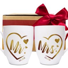 two coffee mugs in front of a box with a red bow on the side