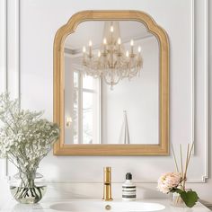 a bathroom vanity with a large mirror above it and flowers in vases on the counter