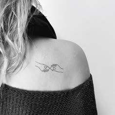 a woman with a tattoo on her shoulder holding the hand of another person's arm