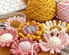 crocheted flowers and balls of yarn sitting on a table