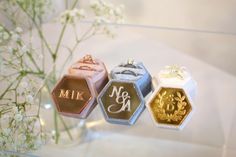 three wedding rings and two engagement rings are on a glass display case with flowers in the background