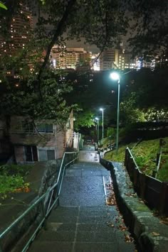 an alley way with stairs leading up to the street lights at night in a city