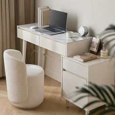 a laptop computer sitting on top of a white desk next to a potted plant