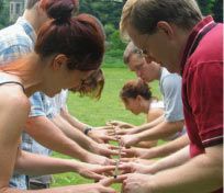 a group of people standing next to each other in a field with their hands together