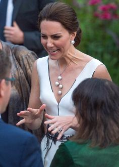 a woman in a white dress talking to two men