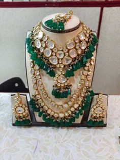 a necklace and earring set with green stones on display in front of a white table