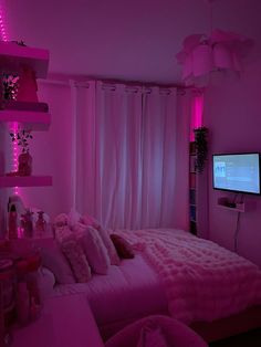 a bedroom with pink lighting and lots of pillows on the bed, in front of a flat screen tv