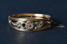 An ornate 9 carat gold, Edwardian bangle with what looks to be a star and thistle pattern. It has seen some wear and has taken some knocks (with dings) as a result but is still completely intact with no missing pieces or stones (please refer to images). There are a total of three small rubies with the largest being surrounded by a single row of diamond chips.  One of our favourite features lies in the detailing where you can see very small millegrain patterns applied around the entire bangle. Th Antique Yellow Gold Bangle For Formal Occasions, Victorian Style Yellow Gold Bracelets With Intricate Design, Ornate Hallmarked Yellow Gold Bracelet, Victorian Gold Bracelet For Formal Occasions, Heirloom Bangle With Intricate Design For Formal Occasions, Formal Cuff Bracelet With Intricate Design, Heirloom Cuff Bracelet With Intricate Design For Formal Occasions, Vintage Yellow Gold Hallmarked Cuff Bracelet, Victorian Bangle With Intricate Design For Formal Occasions