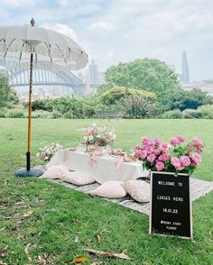 a table set up with flowers and an umbrella for a wedding reception in the park