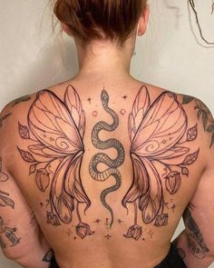 a woman with tattoos on her back is wearing a snake and wings tattoo