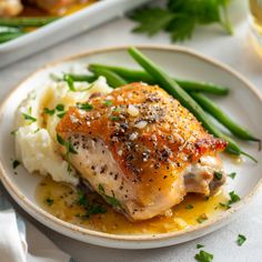 a white plate topped with chicken, mashed potatoes and green beans