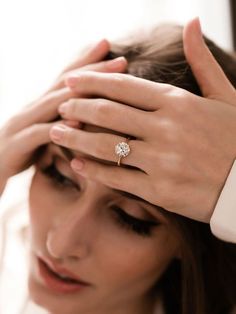 a woman holding her hand to her head with a diamond ring on it's finger