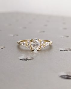 a diamond ring sitting on top of a silver surface with drops of water around it