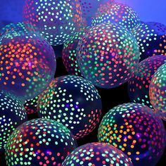 many colorful balls with dots on them in the dark