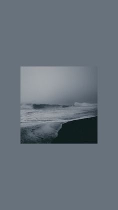 black and white photograph of ocean waves crashing on the beach with an overcast sky