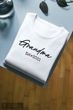 Personalized Grandma Est. white t-shirt. Please use the personalized section to write the year you would like printed on the t-shirt. *Please see listing photos for sizing info, additional color options and instructions for ordering multiples. *Care Instruction: Turn inside out and wash in cold water. Tumble dry using low heat setting. Do not dry clean. Do not iron directly on design.  *Processing And Shipping Processing 1-3 days. First Class shipping with tracking is 2-5 business days(after pro Personalized White T-shirt For Father's Day, Customizable White T-shirt For Personalized Gift, Personalized White Graphic Print T-shirt, Custom Print White T-shirt For Personalized Gift, White T-shirt For Father's Day Gift, White Letter Print T-shirt As Gift, Personalized White Top With Name Print, Personalized White T-shirt As Gift, Personalized Name Print White Top