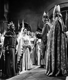 black and white photo of people dressed in medieval costumes standing around each other with crowns on their heads