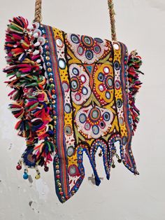 a multicolored bag hanging from a rope with beads and tassels on it