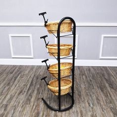 a rack with five baskets on it in front of a white wall and wood floor