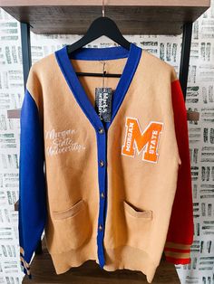 Make a bold statement and wear your Morgan State pride with this one-of-a-kind and comfortable cardigan sweater, perfect for any alumni, students or supporters. Made with the highest quality materials, this sweater is designed to keep you warm and cozy while representing Morgan State. Features:- Official Morgan State University logo embroidered on the chest- Large "M" Chenille patch- Classic cardigan design with a tortoise shell button-up front- Two front pockets (deep enough to fit a phone and Morgan State University Decision Day, Fall Streetwear Cardigan With Ribbed Cuffs, Fall Cardigan With Ribbed Cuffs For Streetwear, Casual Color Block Cotton Cardigan, Casual Cardigan With Ribbed Cuffs For College, Brown Fall Cardigan For Streetwear, Fall Streetwear Brown Cardigan, Brown Cardigan For Fall Streetwear, Collegiate Long Sleeve Cotton Cardigan