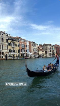 a gondola with several people in it going down the water next to buildings