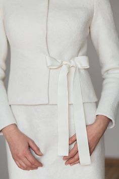 a woman wearing a white coat with a tie around her waist