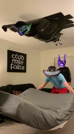 a person in a room with a bed and some fake animals on the ceiling above them