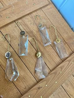 five clear glass items are hanging from hooks on a wooden table with confetti sprinkles