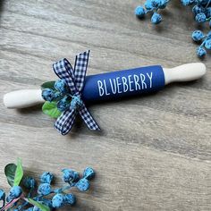 a blueberry rolling pin sitting on top of a wooden table next to some flowers