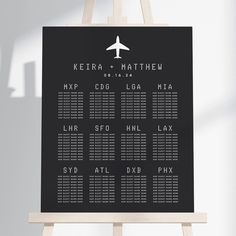 a black and white wedding seating chart with an airplane on the back, sitting on a easel