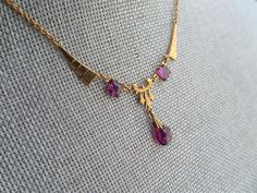 STUNNING beautiful German Made 1920s Art Deco necklace! This is a beauty with strong Art Deco design and gorgeous deep purple amethyst color glass stones.The necklace is set in gold tone setting and is marked Germany on the back. It measures about 16.5 inches in length and the centre drop is about 1.25 inches, all in wonderful like new condition-looks seldom worn, definitely gift worthy! Enjoy wearing this gorgeous Deco necklace and adding it to your collection. We combine shipping and ship inte Art Deco Yellow Gold Necklace For Formal Occasions, Art Deco Pendant Necklace For Formal Occasions, Formal Art Nouveau Necklace, Art Deco Jewelry With Vintage Charm For Vintage Events, Art Deco Gemstone Necklace For Anniversary, Classic Amethyst Necklaces For Wedding, Victorian Purple Necklace For Anniversary, Art Deco Hallmarked Jewelry For Vintage Events, Art Deco Oval Necklaces For Weddings