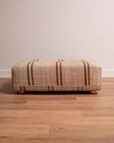 a brown striped ottoman sitting on top of a hard wood floor