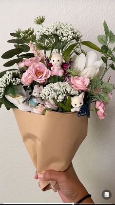 a person holding a bouquet of flowers in their hand and stuffed animals on the side