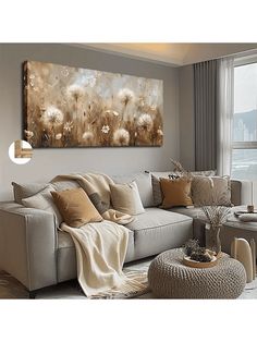 a living room scene with focus on the couch and large painting in the background that has dandelions all over it