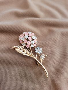 The brooch has a single pink and white enameled lilac flower with leaves and a smaller full crystal accented flower.  Gold plated. Wedding Enamel Pin Brooch, Elegant Pink Enamel Brooch Pin, White Flower Enamel Pin For Wedding, Elegant Pink Enamel Pin For Gift, Elegant Pink Enamel Pin, Formal Pink Brooch Lapel Pin, Elegant Rose Gold Lapel Pin Brooch, Formal Pink Lapel Pin Brooch, Elegant Pink Wedding Brooches