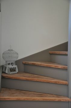 a white birdcage sitting on top of some wooden steps next to a wall