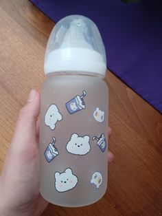 someone is holding a baby bottle with stickers on it