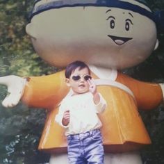 a young child standing in front of a large stuffed animal with sunglasses on it's head