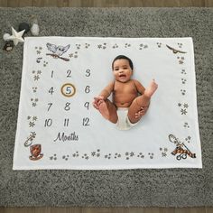 a baby laying on top of a white blanket with numbers and stars around it,